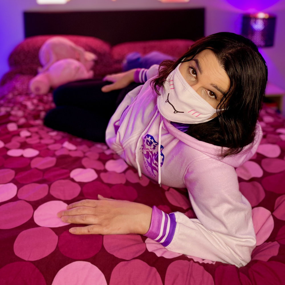 Lying on bed, wearing pink and white Beatmania IIDX hoodie