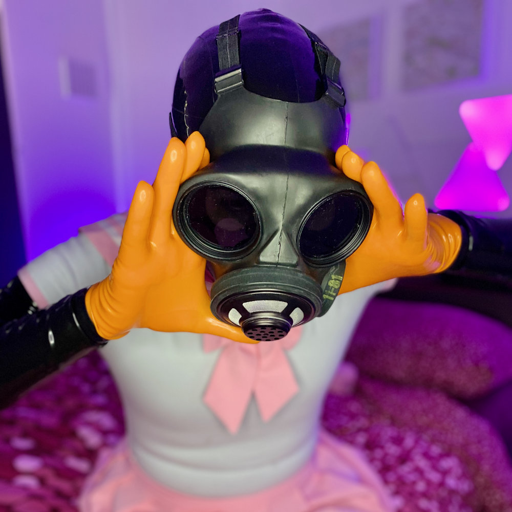 Dressed in full latex catsuit, wearing a pink and white seifuku and orange latex gloves. Trying to remove the gas mask bonded to my face