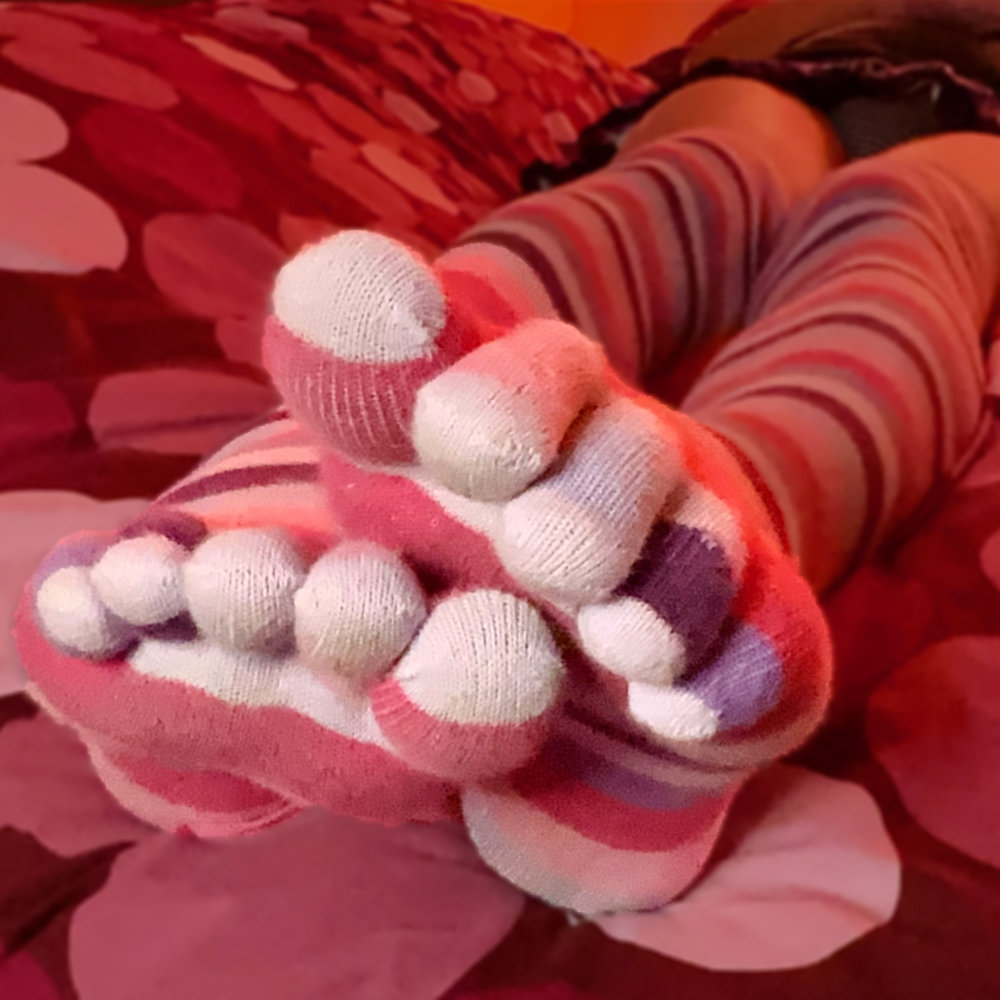 A close-up of Rina’s feet in stripy purple and pink toe socks, the the toes and soles visible to camera