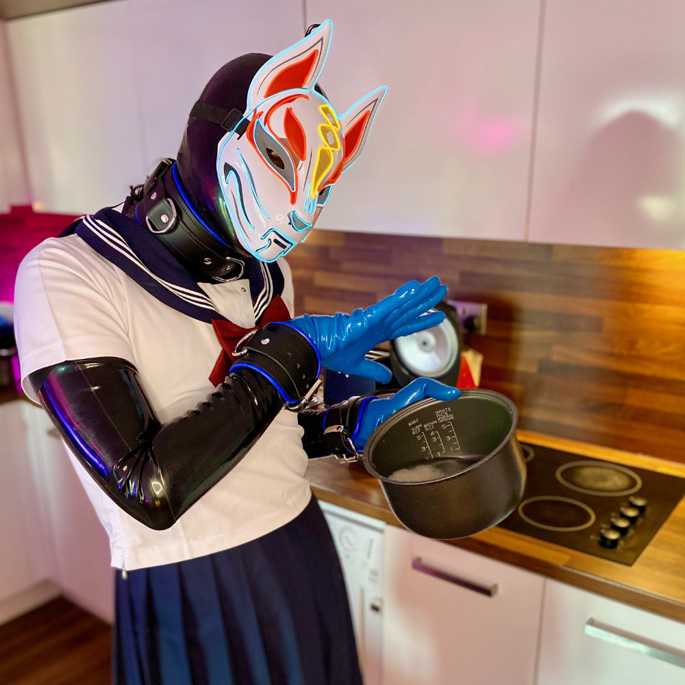 Black latex catsuit, blue latex gloves and toe socks, fox mask, Japanese seifuku. Washing rice in a bowl.